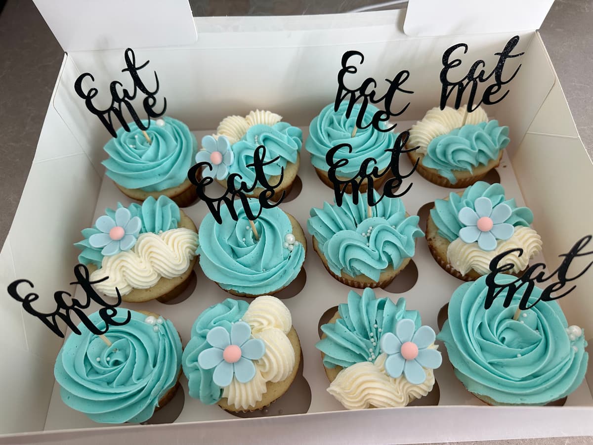Teal cupcakes with Eat Me toppers and flower decorations